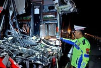 Anggota Satlantas Polres Pekalongan menunjukkan bangkai bus bagian depan yang ringsek akibat menghantam truk tronton di Tol Pemalang - Batang, Senin (27/7/26) dini hari. Foto : Istimewa